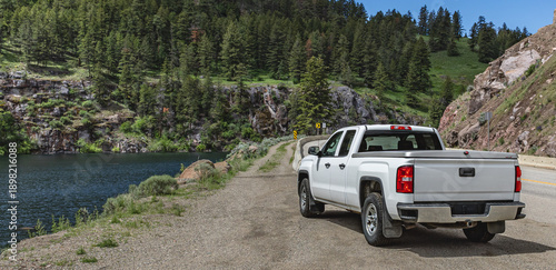 Pickup truck on the beautiful road along the mountain river and forest.