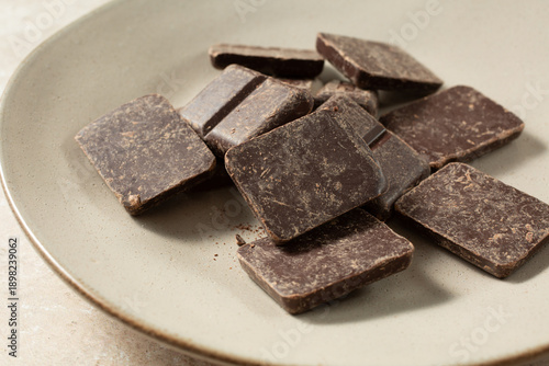 A view of a pile of dark chocolate pieces, on a plate.