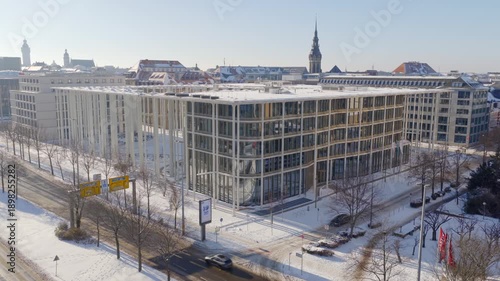 Wallpaper Mural Modern architecture SAB Bank in snowy Leipzig: The glass office building on Dittrichring stands in contrast to the historic spire of St. Thomas Church under a clear winter sky. Torontodigital.ca