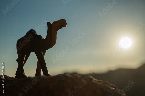 Fototapeta Rzeźba wielbłąda na tle skał i błękitnego nieba – pustynny krajobraz w słoneczny dzień