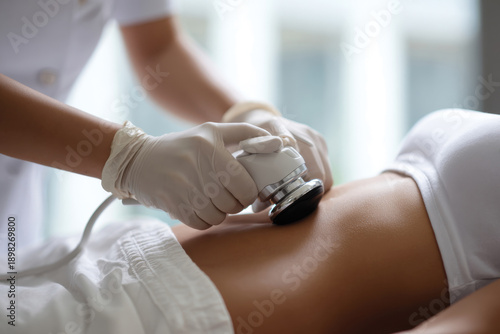 An ultrasound treatment administered on a woman's abdominal area, highlighting modern technology in flux and its role in body sculpting and skin rejuvenation.