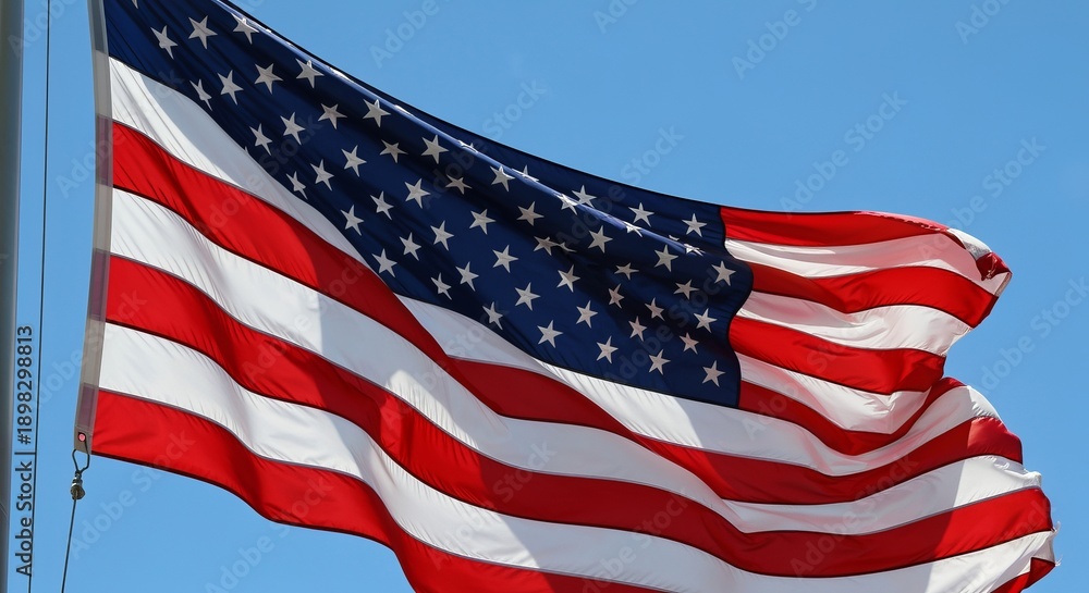 Fototapeta premium A Symbol of Freedom The American Flag Waving Proudly Under a Clear Blue Sky During Daytime