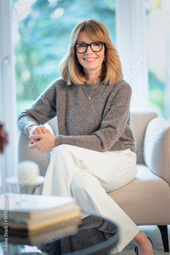 Blond haired woman relaxing in an armchair in her modern home