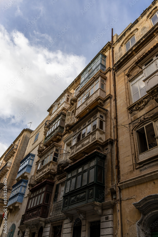Fototapeta premium Facades of old buildings with windows and colorful balconies on the streets of Valletta, Malta.