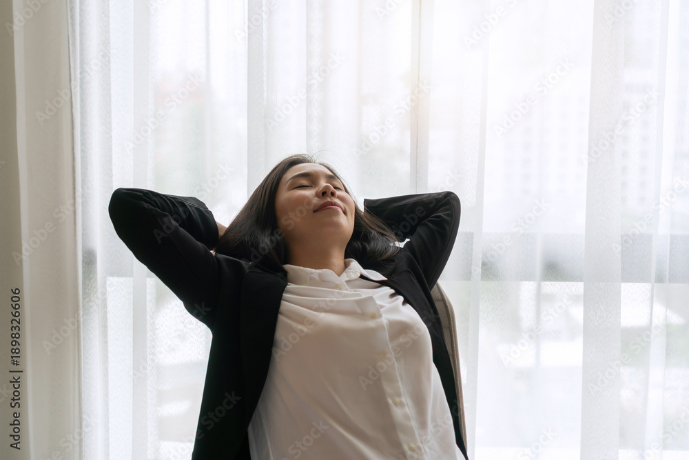 Fototapeta premium Businesswoman relaxed or stretched, leaning back in her office chair, hands clasped behind her head