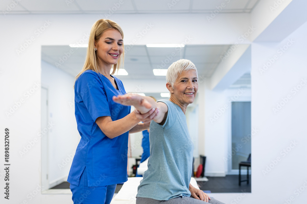 Fototapeta premium Shoulder pain exercise. Physical therapist helping senior woman with arm mobility in clinic. Healthcare and medicine concept, elderly patient during rehabilitation for muscle and joint problems.