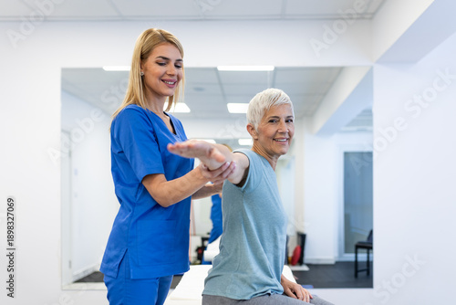 Shoulder pain exercise. Physical therapist helping senior woman with arm mobility in clinic. Healthcare and medicine concept, elderly patient during rehabilitation for muscle and joint problems.