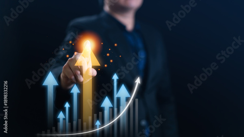 Businessman touching glowing orange growth arrow pointing up with digital financial graph background. Concept of corporate success, economic profit increase, leadership, and future business strategy.