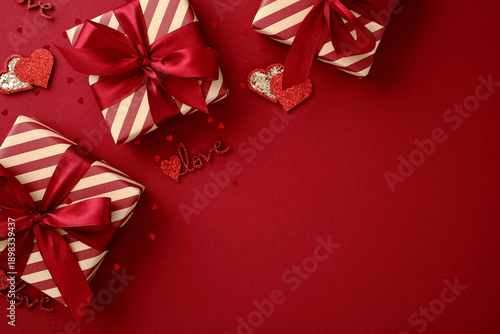 Festive Valentine's gift boxes with red ribbons and hearts on a red background. © photoguns