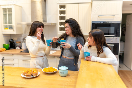 Friends enjoying breakfast, eating and laughing in kitchen