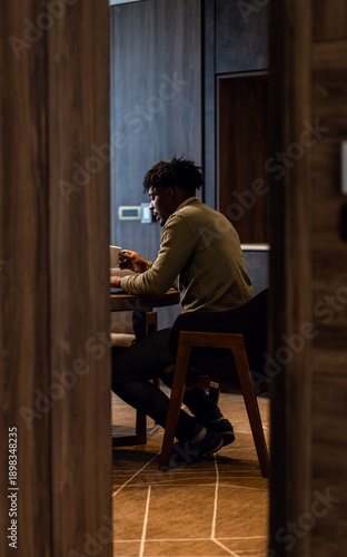 Businessman working remotely on laptop while sitting at table in hotel room.