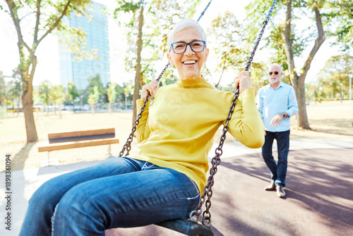 Valokuva Happy active senior couple having fun on a swing in park outdoors