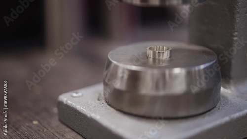 Professional hydraulic press shaping silver jewelry ring.
