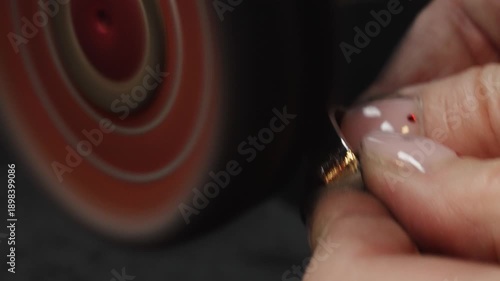 Professional jeweler polishing gold ring on rotary machine.