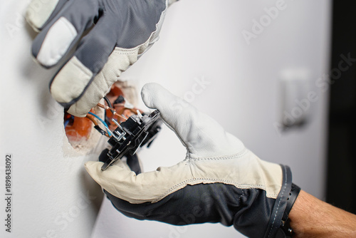 Wallpaper Mural Electrician hands wearing protective gloves connecting exposed copper electrical wires to wall light switch. Concept of electrical safety, professional repair, home renovation and maintenance Torontodigital.ca