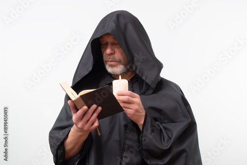Photos Bearded monk in hood focused reading text, isolated.
