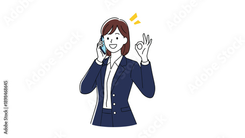 Businesswoman in a formal navy suit talks on a mobile phone and gives an okay hand sign with a white background.