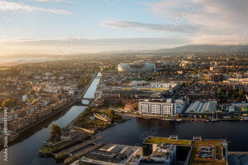 Aerial view of Aviva Stadium gleaming in the distance, juxtaposed against the calm waters and urban sprawl under a soft morning light, Dublin, County Dublin, Ireland.