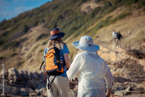Hikers standing on rocky mountain trail resting and enjoying the scenic landscape during trekking adventure wearing backpacks and outdoor clothing representing hiking exploration and active lifestyle 