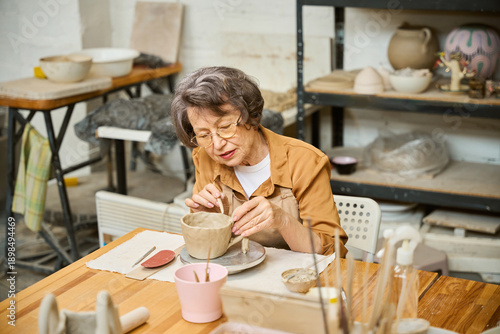 Elderly lady works on a clay bowl in ceramics studio