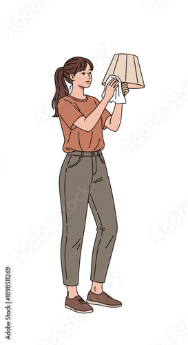 Young woman cleaning lamp shade with cloth in minimalist interior  
