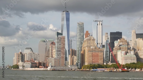 New York City Manhattan Downtown skyline from ferry boat to Liberty Island, United States. Financial District cityscape, World Trade Center skyscraper tower. Urban buildings architecture. Rain clouds.