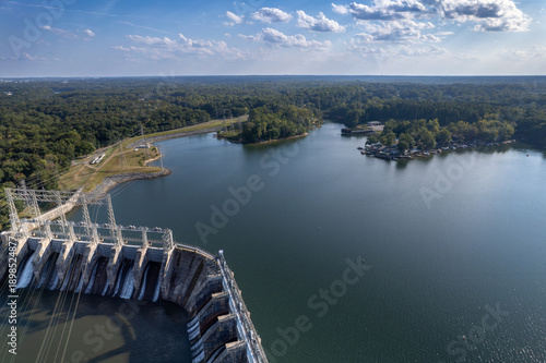 Late afternoon sun shines through clouds onto Lake Wylie flowing over dam in Catawba River