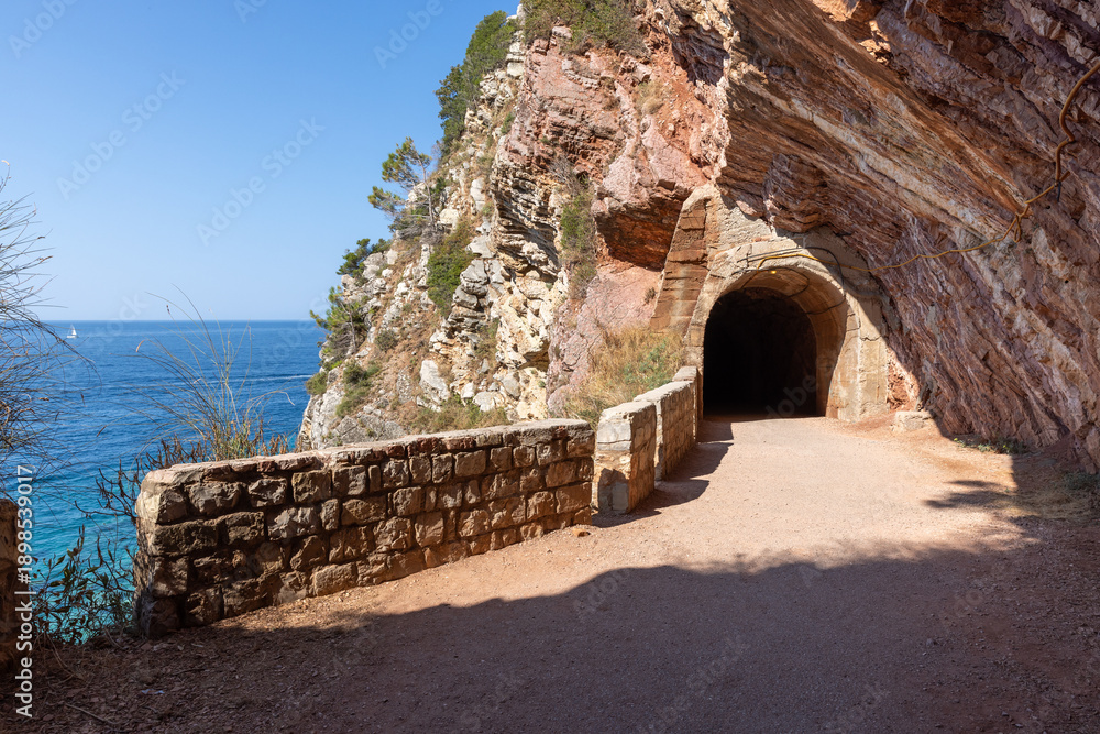 Fototapeta premium A rugged coastal scene features a tunnel carved into a cliff