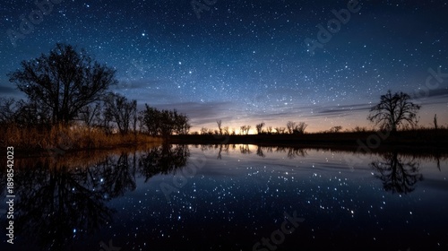 Wetland night sky with stars reflected on smooth, undisturbed water