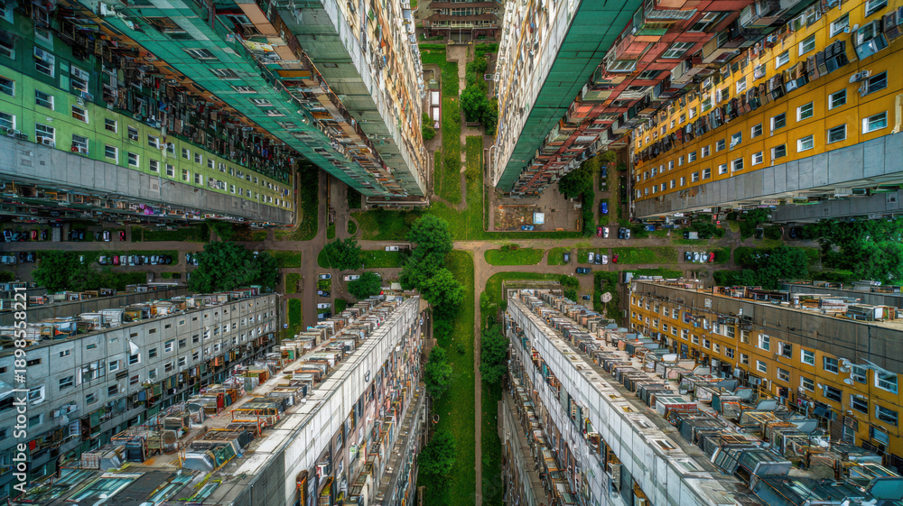 Fototapeta premium Real estate business market, house home building purchase sale. An aerial view of a multistory residential area, with buildings featuring windows, vehicles on the ground, and lush green grass.