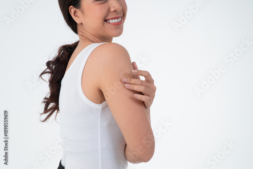 Radiant Self-Embrace: A smiling woman, bathed in natural light, tenderly touches her shoulder, exuding a sense of contentment and self-love. A portrait of confidence.
