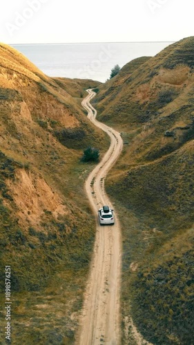 Beautiful nature landscape and white tourist car traveling to the sea in a deep canyon. Amazing place to travel. View from the drone on the car. A drone watching a car.