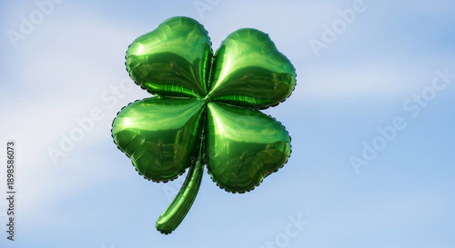 Shiny green four leaf clover against a serene blue sky with white clouds symbolizing luck and nature