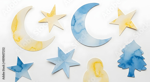 A collection of blue and yellow paper cutouts of moons, stars, and a tree on a white background