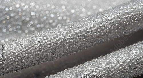 Wet gray fabric texture covered in small water droplets shows waterproof material closeup.