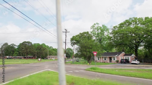 Moving past middle lower class poor neighborhood street homes outside downtown capital city Montgomery, Alabama in historic suburb community with houses, buildings, sidewalk, cars, driveways, and road