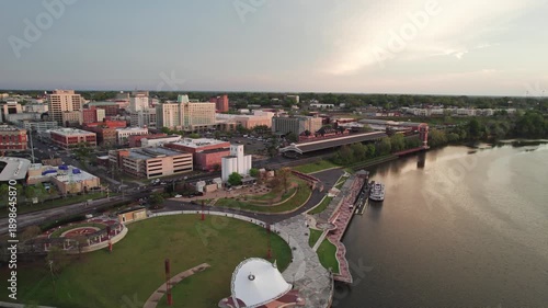 Aerial drone landscape view of downtown Montgomery, Alabama riverfront water park along gun island shoot river with baseball ballpark stadium, green lawn, buildings, high-rises, and capital city roads
