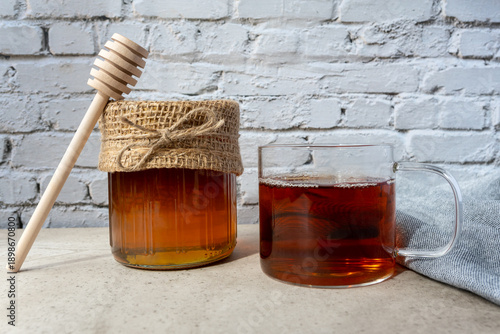 Glass bowl of natural honey, cup of tee and wood spoon on the table.