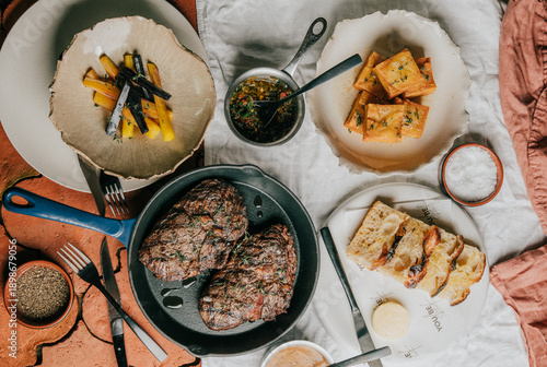 Quadro em tela A table with a variety of food items including meat, bread, and vegetables