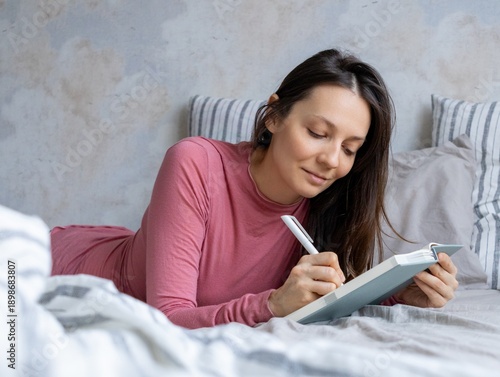 Wallpaper Mural thoughtful woman lies in bed writes in diary, writes emotions, wish list notebook. mental health care, psychotherapy. female writer plans her workday, makes to do list. female writer creates article. Torontodigital.ca