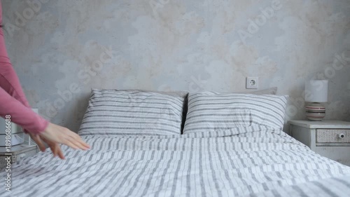 Wallpaper Mural woman makes bed, puts pillows and blanket on bed, smoothes sheet. cleaning house, change of bed linen. freshness and purity of home textiles. taking care of health of household. maid at the hotel. Torontodigital.ca