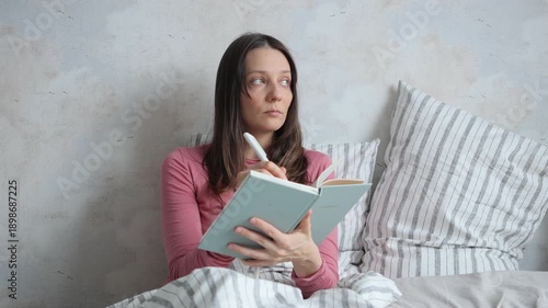 Wallpaper Mural woman sits on bed and writes in diary. lady writes emotions wish list in notebook. mental health care, psychotherapy. female writer plans workday makes to do list. female writer creates article, book. Torontodigital.ca