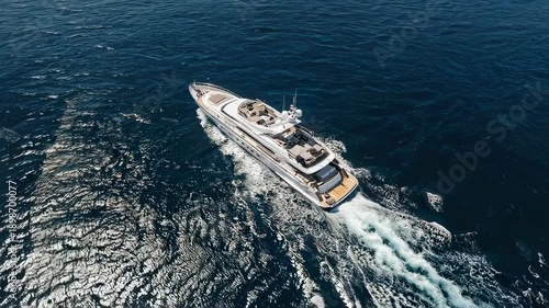 Overhead view of a large, white yacht cruising through deep blue ocean waters