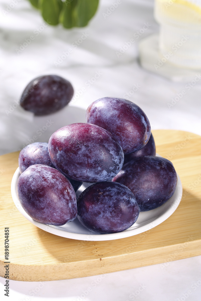 Fototapeta premium Fresh Purple Plums on Wooden Board - Sweet Healthy Fruit Snacking Style