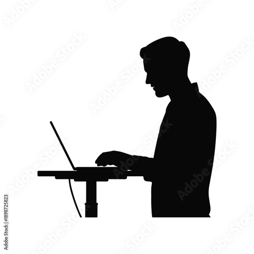 A silhouette of a man working on a laptop at a desk