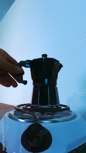 Person making morning coffee with moka pot on an electric stove