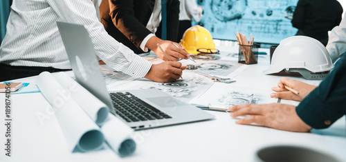 Canvastavla A diverse group of professionals engaged in collaborative planning over construction documents in a modern office setting