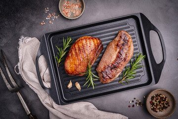 Roasted or grilled duck breast with the addition of aromatic herbs on a grill pan, top view. Food recipe background. Close up. High quality photo