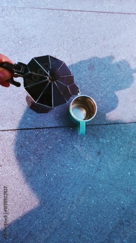 Hand pouring italian moka pot coffee outdoors