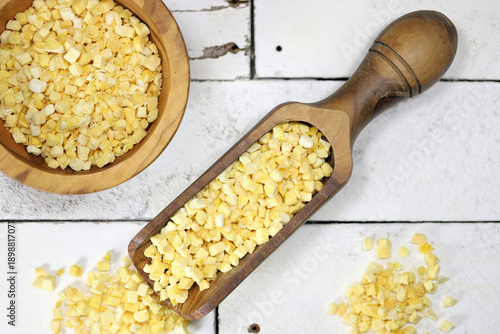freeze-dried mango cubes in olive wood tableware on rustic wooden background